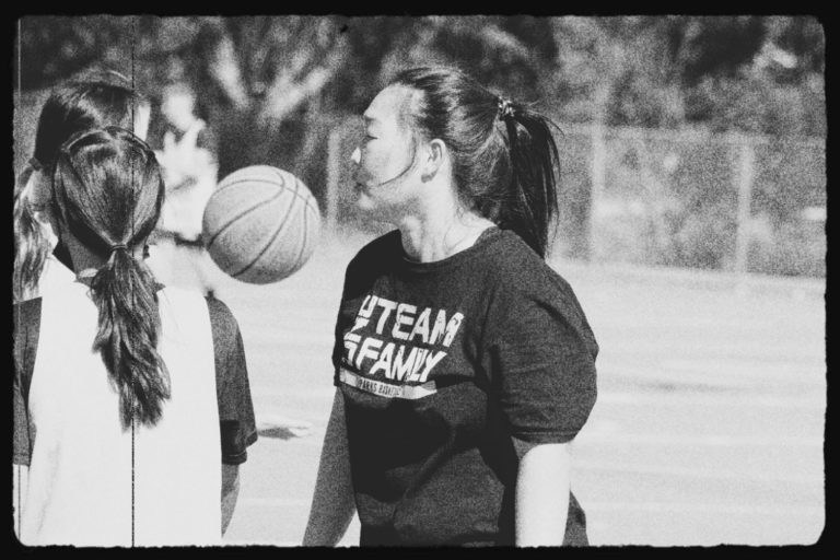 A coach is seen at Basketball practice working with students