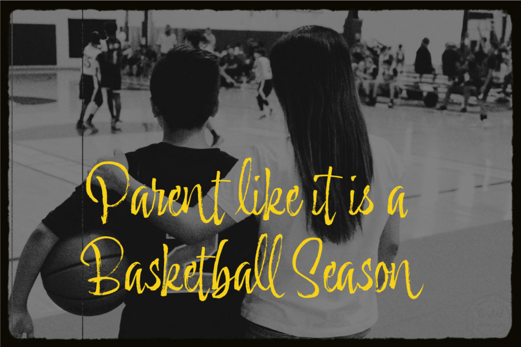 A mother is standing court side watching a basketball game while having her arm around her son. He is wearing a basketball jersey and holds a basketball. The text in yellow says: "Parent like it is a basketball season".