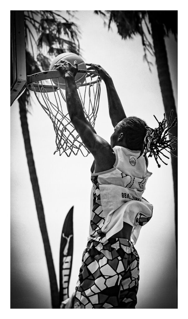 A male basketball player is seen dunking the ball during an outdoor game at Venice Beach in California.